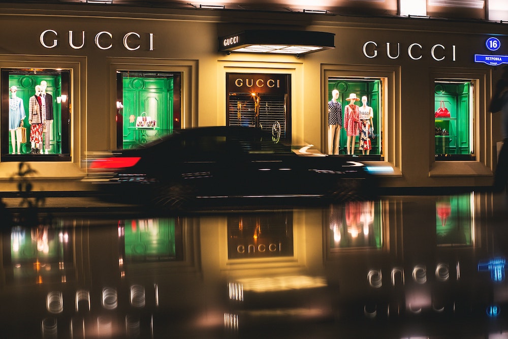 A blurred photo of a car outside of a Gucci store at night.